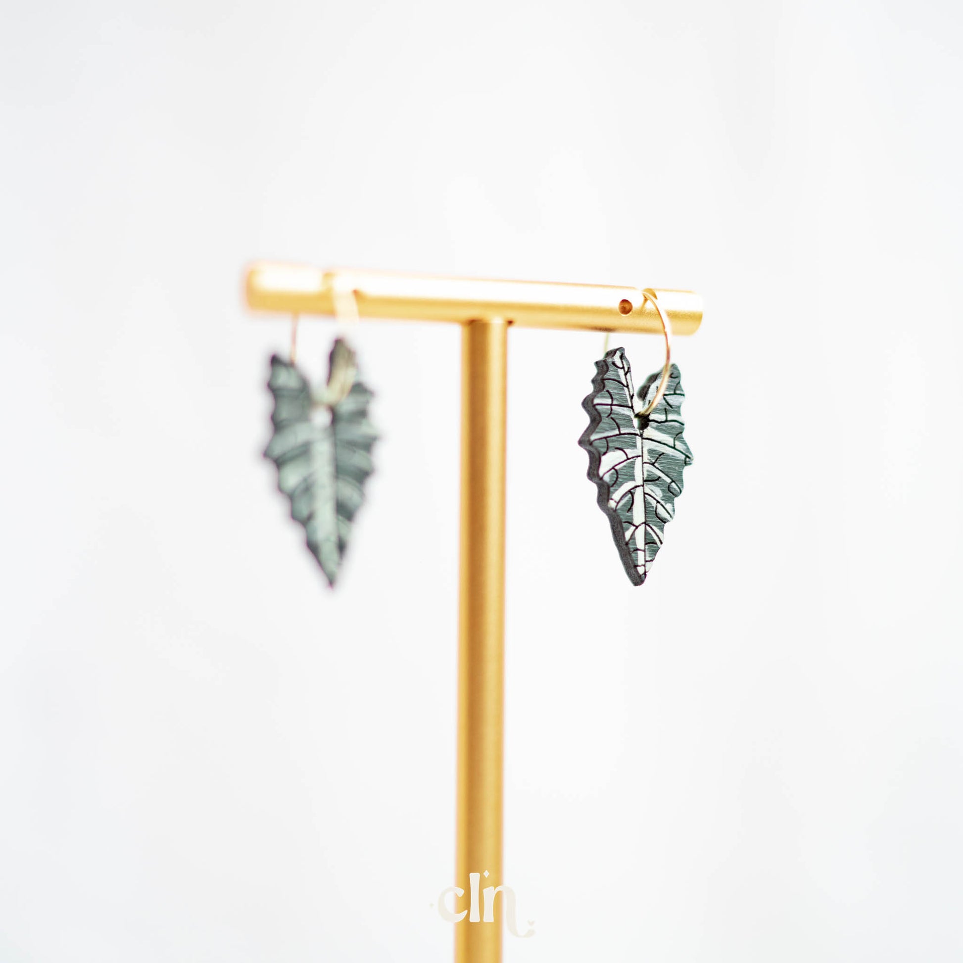 a pair of green leaf shaped earrings on a stand