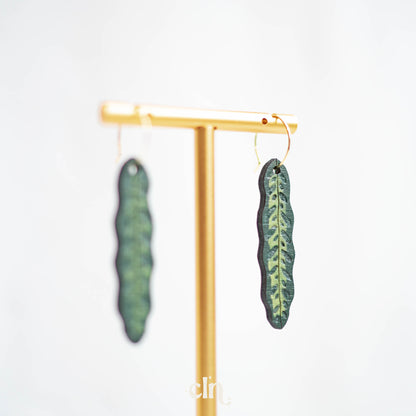 a pair of earrings with green leaves hanging from them