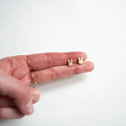 a person's hand holding a tiny gold ring