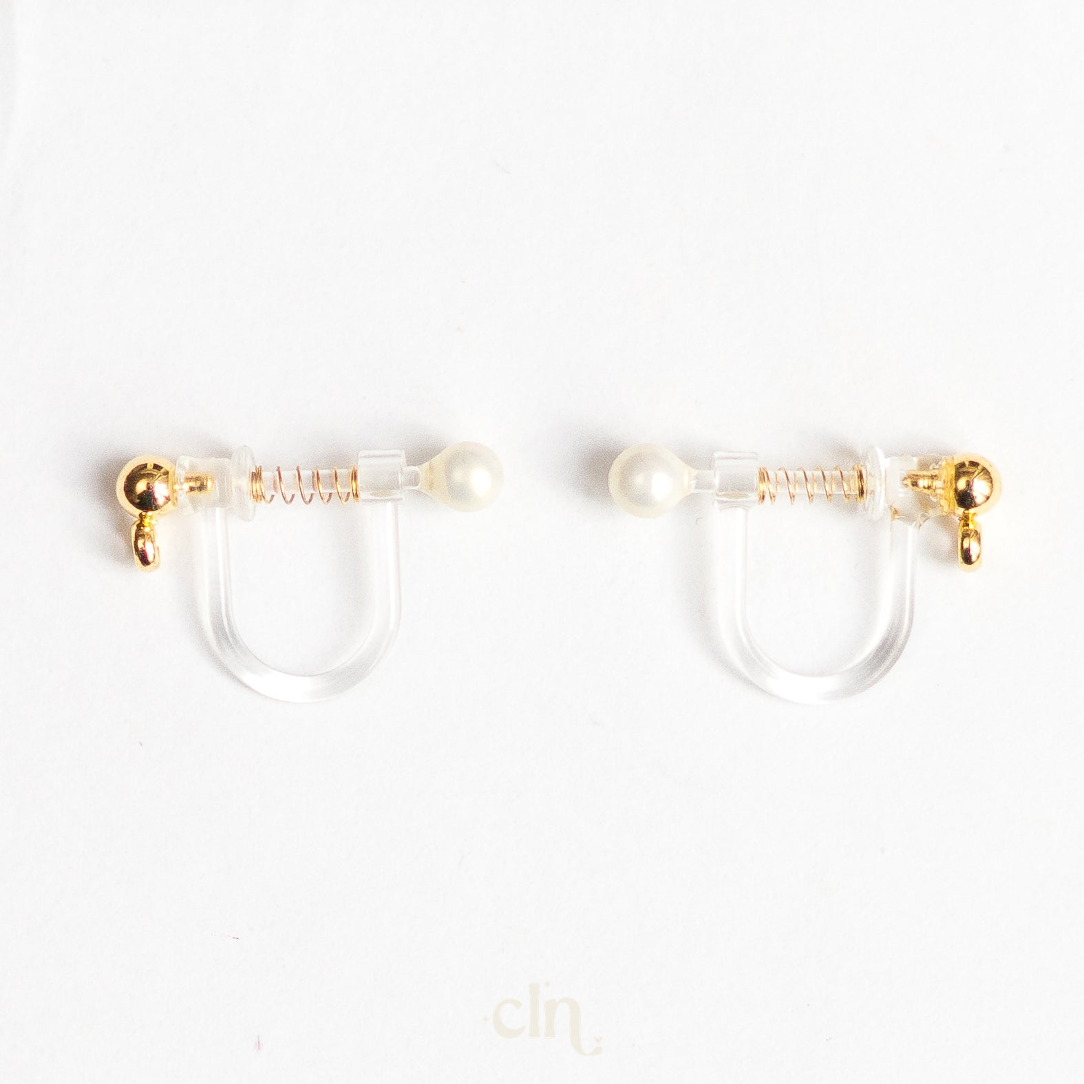 a pair of gold and pearl earrings on a white background