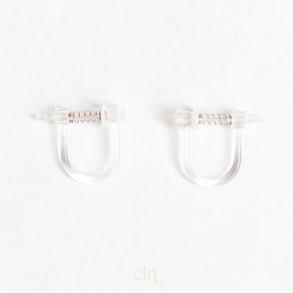 a pair of clear plastic ear clips on a white background