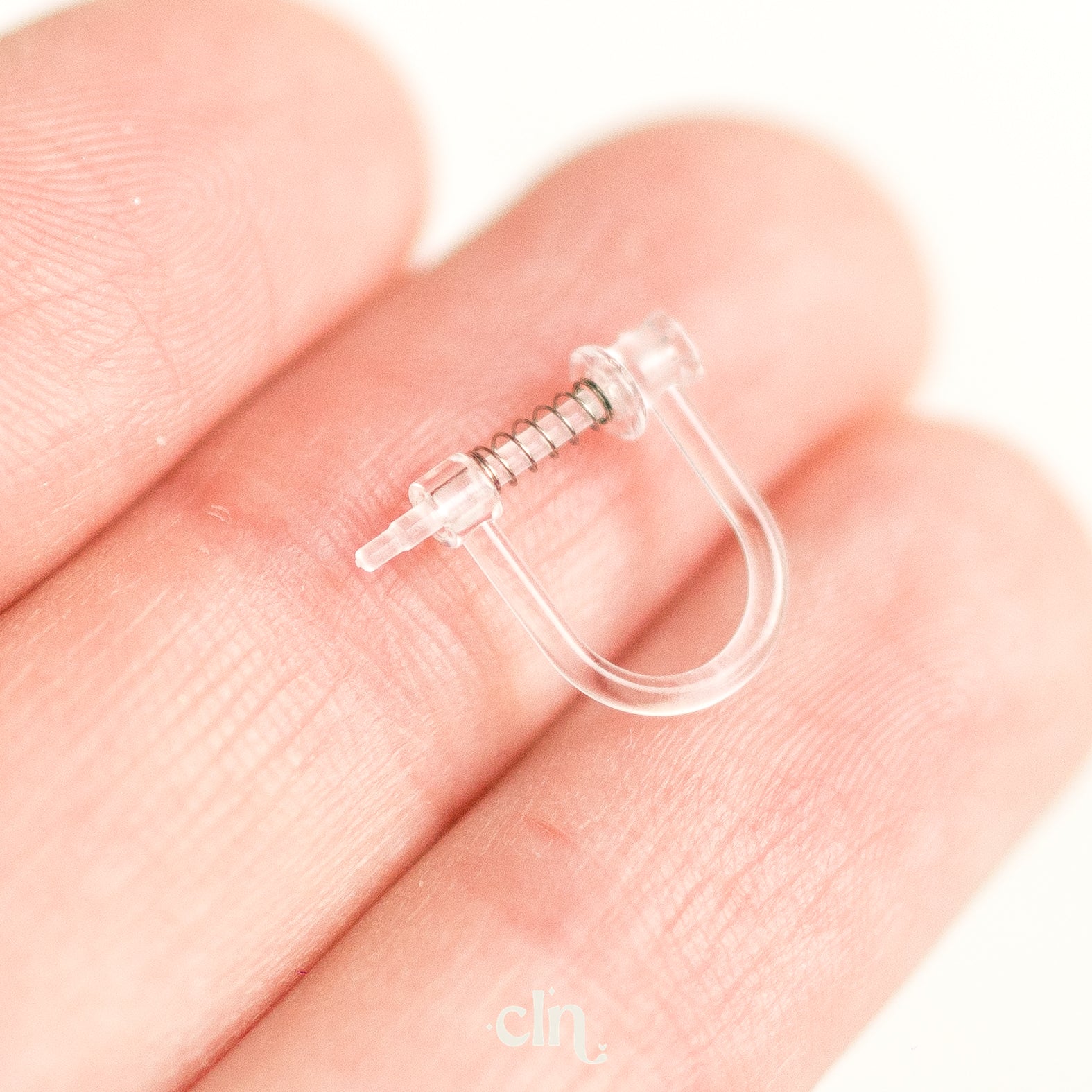 a person's hand holding a small nose ring