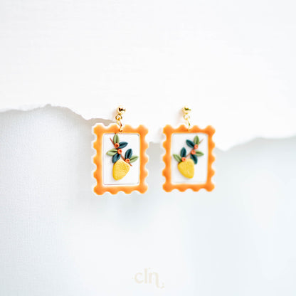 a pair of earrings with a picture of a pineapple